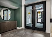 Thumbnail 16 of 23 - A hallway with a green wall and a mirror above a cabinet.