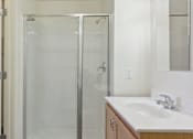 Thumbnail 21 of 26 - A white bathroom with a sink, mirror, and shower.