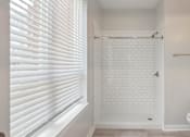 Thumbnail 4 of 25 - A white bathroom with a toilet, sink, and a shower with a white tile wall.