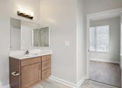 Thumbnail 5 of 25 - A bathroom with a white toilet, a sink with a wooden cabinet and a mirror above it.