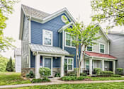 Thumbnail 1 of 18 - A blue house with a red roof is in front of a grey house.