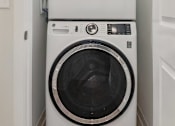 Thumbnail 6 of 25 - A white front load washing machine with a black door is in a white doorway.