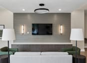 Thumbnail 8 of 23 - A modern living room with a grey sofa, green armchair, and a television mounted on the wall.
