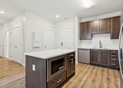 Thumbnail 20 of 23 - A kitchen with a white counter top and wooden floors.