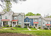 Thumbnail 11 of 18 - A row of houses with red roofs and stone pillars.
