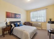 Thumbnail 11 of 17 - a bedroom with a bed and a chair in front of a window