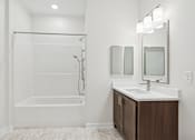 Thumbnail 2 of 23 - A white bathroom with a white tub and sink.