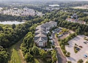 Thumbnail 2 of 21 - an aerial view of a large building surrounded by trees and a river