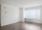 Thumbnail 14 of 16 - A large empty room with a window and a door leading to a bathroom.