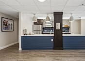Thumbnail 65 of 75 - A reception area with a blue counter and a brown pillar.