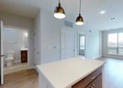 Thumbnail 7 of 18 - A white kitchen with a large island and pendant lights.