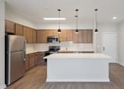Thumbnail 7 of 25 - A modern kitchen with wooden cabinets and a white island.