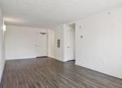 Thumbnail 15 of 16 - A room with white walls and wooden flooring with two doors.