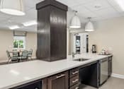Thumbnail 75 of 75 - A kitchen with a white counter top and dark brown cabinets.