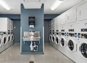 Thumbnail 66 of 75 - A row of washing machines are lined up in a laundry room.