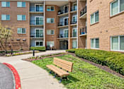 Thumbnail 57 of 75 - A large apartment complex with a red curb and a bench in front.