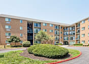Thumbnail 55 of 75 - A large apartment complex with a red curb and green bushes in the front.