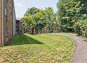 Thumbnail 3 of 75 - A pathway leads through a grassy area between two rows of buildings.