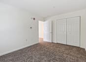 Thumbnail 14 of 21 - a bedroom with two doors and a carpeted floor