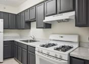 Thumbnail 11 of 16 - A white refrigerator sits in a kitchen with dark grey cabinets.