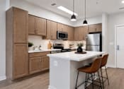 Thumbnail 23 of 25 - A kitchen with brown cabinets and a white island.