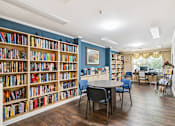 Thumbnail 5 of 14 - A room with a large bookshelf filled with books and a table with chairs.