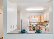 Thumbnail 9 of 14 - A kitchen with a white fridge and wooden cabinets.