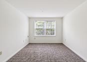 Thumbnail 13 of 14 - A room with a window and carpeted floor.