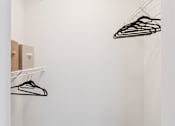 Thumbnail 14 of 14 - A white closet with a hanger and a light on the ceiling.