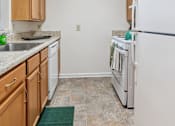 Thumbnail 7 of 21 - A kitchen with white appliances and wooden cabinets.