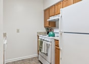 Thumbnail 9 of 21 - A kitchen with white appliances and wooden cabinets.