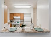 Thumbnail 10 of 21 - A kitchen with a granite countertop and a white fridge.
