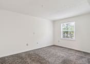 Thumbnail 15 of 21 - A room with a carpeted floor and a window showing a view of trees outside.