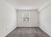 Thumbnail 14 of 21 - A room with a window and carpeted floor.