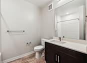 Thumbnail 15 of 17 - A white toilet sits in a bathroom next to a white sink.