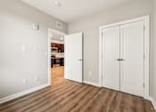 Thumbnail 13 of 17 - A room with white walls and wooden floors has two white doors.