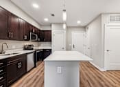 Thumbnail 12 of 17 - A kitchen with dark brown cabinets and a white island.