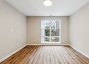 Thumbnail 5 of 17 - A room with wooden floors and a large window.