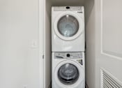 Thumbnail 22 of 22 - A white washing machine and dryer in a small laundry room.