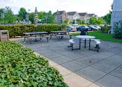Thumbnail 11 of 13 - A side patio with a table and chairs surrounded by green bushes.