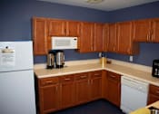 Thumbnail 4 of 13 - Spacious community kitchen fully equipped with a white refrigerator, dishwasher, microwave, and small appliances.