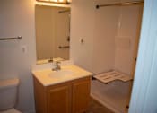 Thumbnail 7 of 13 - A well-lit bathroom with a sink, mirror, and bathtub.