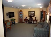 Thumbnail 6 of 13 - Community room with bookshelves, couch, chairs, and a television.