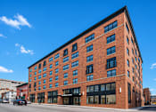 Thumbnail 1 of 33 - A red brick building with a black awning on the ground floor.