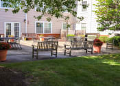 Thumbnail 19 of 21 - A patio with chairs and tables is surrounded by a green lawn.