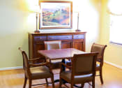 Thumbnail 5 of 21 - A community room table with four chairs and a painting on the wall.