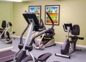 Thumbnail 4 of 21 - A fitness center with exercise equipment and a green wall.