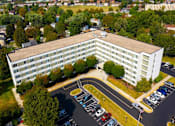 Thumbnail 2 of 11 - large white building with a parking lot in front of it