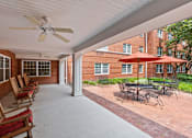 Thumbnail 17 of 18 - a covered patio with chairs and umbrellas in front of a brick building
