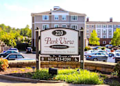 Thumbnail 1 of 15 - Exterior view of Park View at South Pantops, a senior apartment community in the Carriage Hill area near Charlottesville, featuring well-maintained buildings, landscaped grounds, and convenient on-site parking for adults age 62 and better.